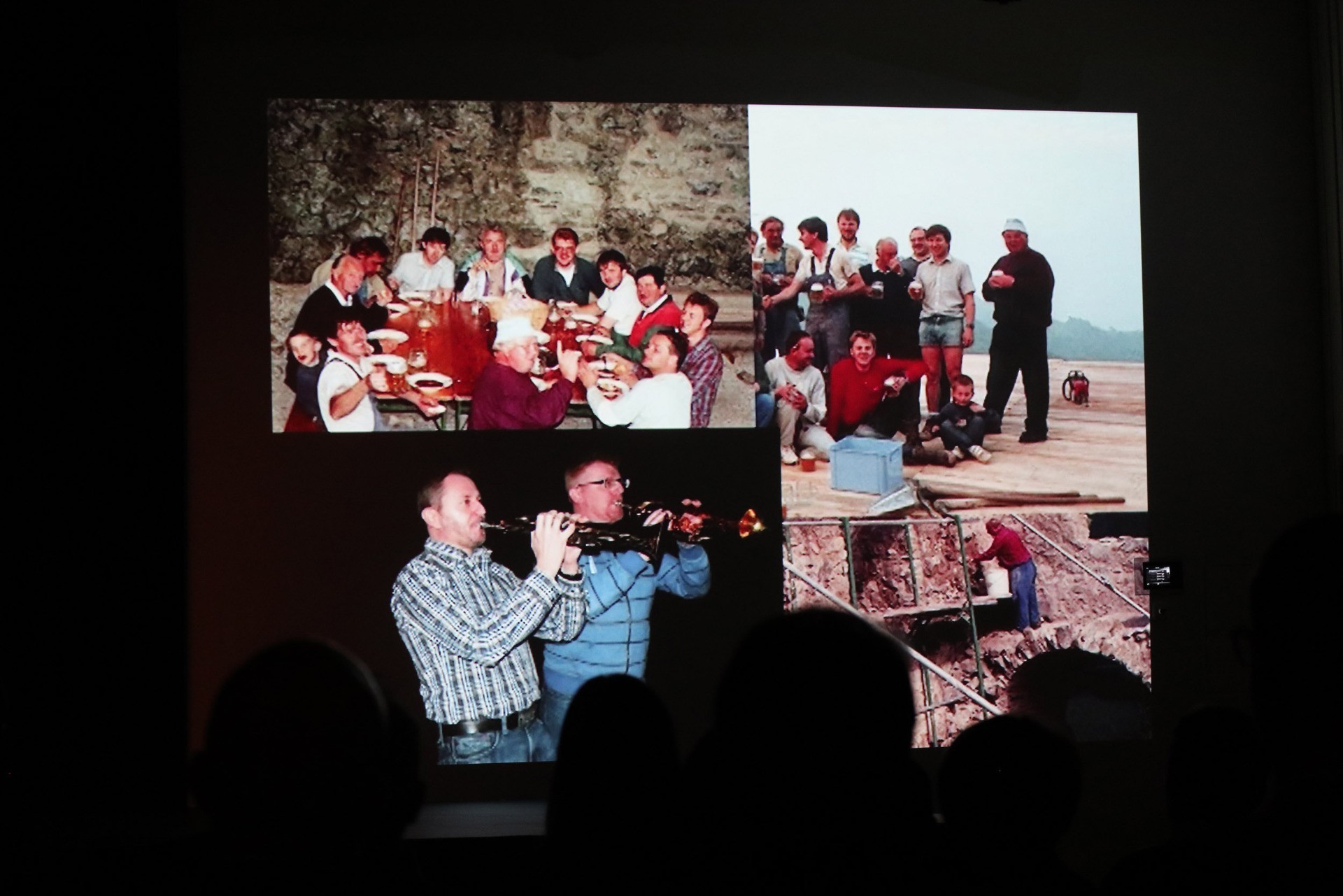 Gruppenfoto von Männern und Jugendlichen bei einer Veranstaltung, darunter ein Mann mit einer Klarinette und Bauarbeiten.