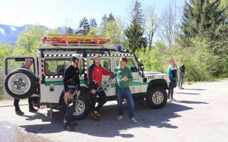 Rotes Ortsfeuerwehrauto mit Einsatzkräften auf unbefestigtem Weg.