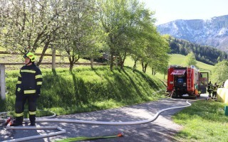 Feuerwehr mit Tanklöschfahrzeug am Straßenrand, ein Einsatzpersonal in voller Schutzkleidung steht bereit.