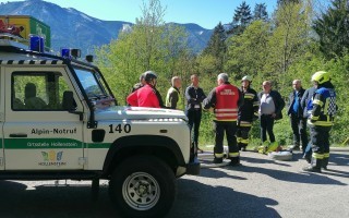 Am Straßenrand stehen mehrere Einsatzkräfte um einen weißen Geländewagen mit der Aufschrift 