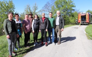 Gruppe von Menschen auf einem Feldweg. Im Hintergrund ein Feuerwehrauto.