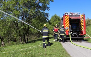 Feuerwehr mit Löschfahrzeug und Einsatzkräften am Einsatzort, Wasserstrahl.