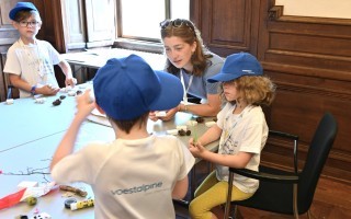 Kinder erstellen gemeinsam mit einer Betreuerin Naturarbeiten am Tisch.