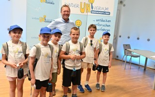 Kinder in blau-weiß karierten T-Shirts stehen in einem Raum.