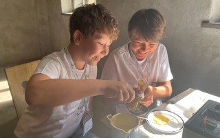 Zwei Kinder am Tisch, die mit einem Eigelb arbeiten.