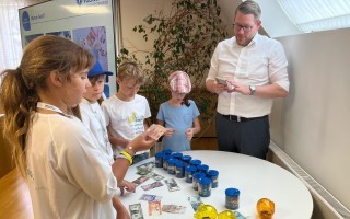 Kinder zählen Geld in Tassen. Auf einem Tisch liegen Geldscheine.