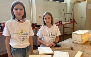 Schülerin in Arbeitskleidung vor Werkbank mit Holzbearbeitungswerkzeugen.