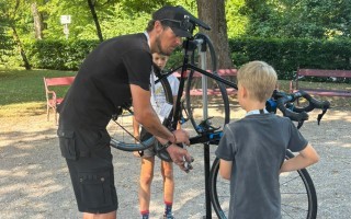 Ein Mann und ein Junge reparieren gemeinsam ein blaues Fahrrad im Freien.
