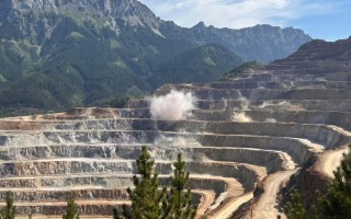 Erdoberabbau mit tiefen Stauseen und Hangwänden, umgeben von bewaldetem Bergpanorama.