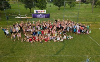 Eine Gruppe von Kindern und Jugendlichen posiert auf einer Wiese mit Fußballfeld.
