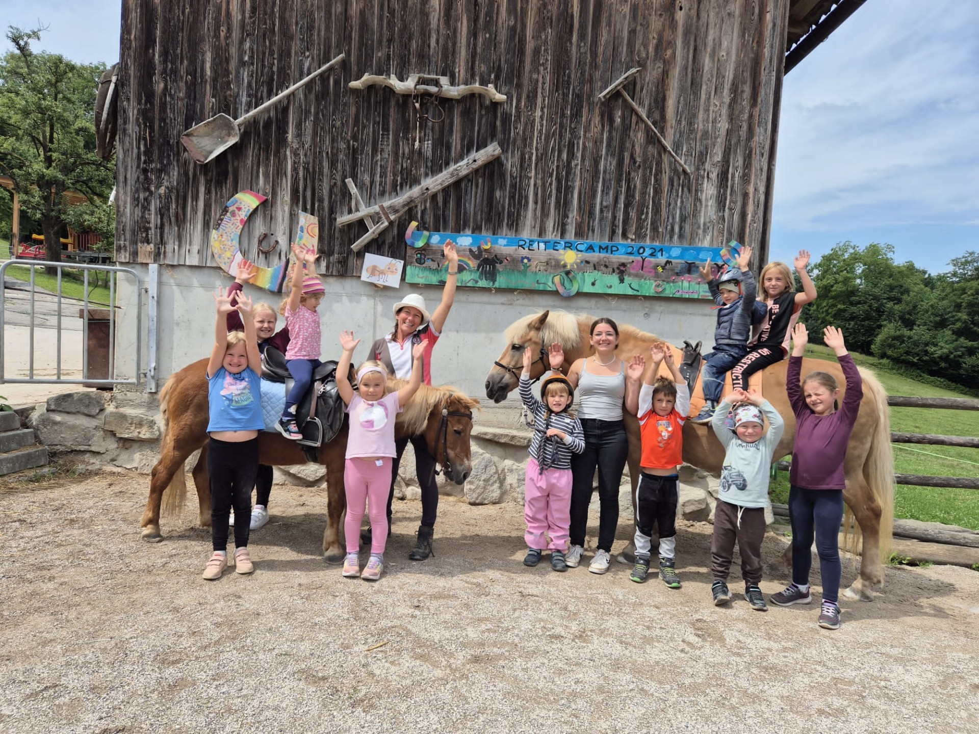 Reitcamp 2021: Mehrere Kinder und Erwachsene reiten auf braunen Pferden auf einer Wiese.