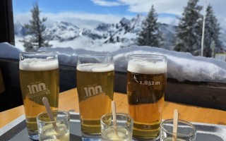 Vier Biergläser mit Schaum auf einem Tisch mit Schnee im Hintergrund.