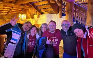 Gruppe von Menschen in dunklen Jacken und Mützen, vermutlich bei einer Veranstaltung oder einem Treffen.