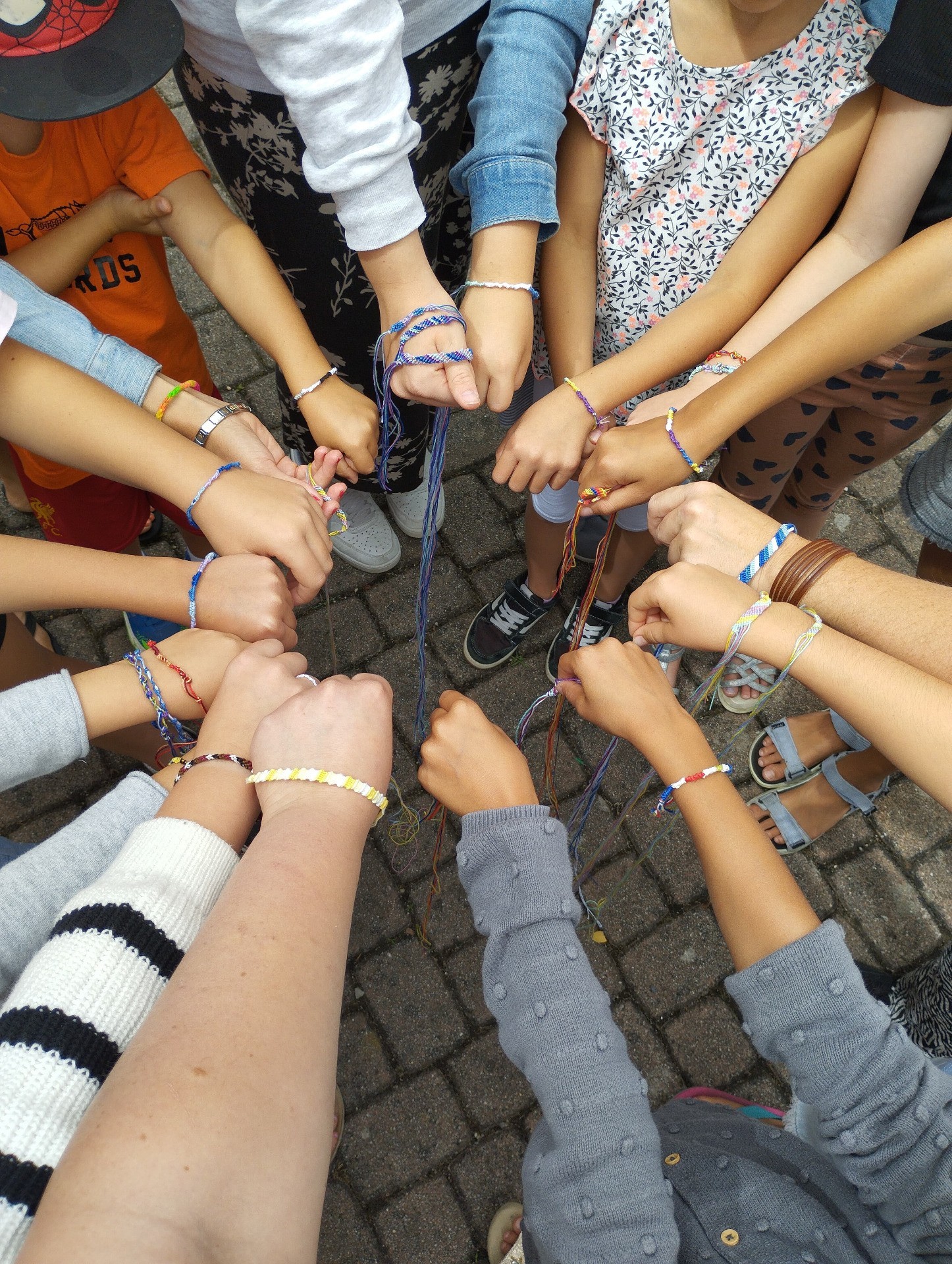 Kinder mit Armbändern, die sich um die Hände legen, auf Pflaster.