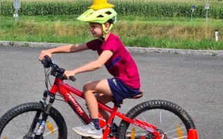Ein Junge fährt auf einem roten Mountainbike mit Schutzkleidung an einem roten Warnkonus vorbei.