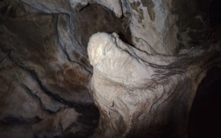 Versteinerte Felsformation in einer dunklen Höhle. Rauhe, strukturierte Oberfläche, sanftes Licht.