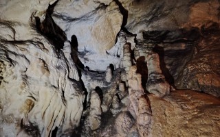 Wand eines grottenartigen, felsigen Innenraums mit Formationen und Schatten.