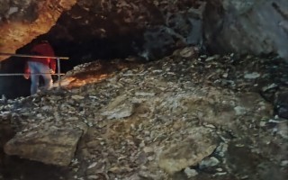 Schieferwände eines dunklen, felsigen Ganges mit einem Betrachter und Zaun.