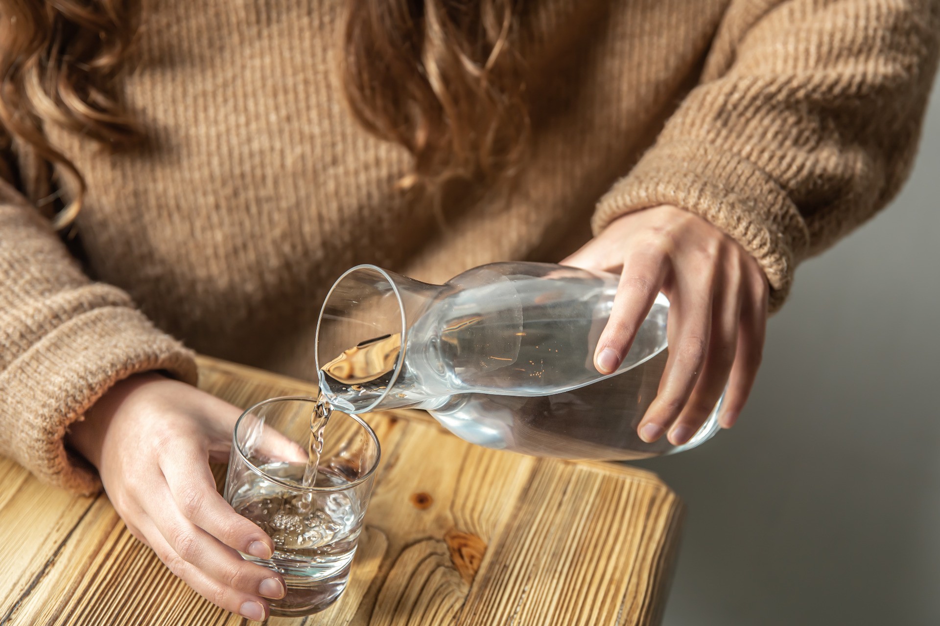 woman-pours-water-into-glass-from-glass-decanter