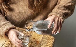 woman-pours-water-into-glass-from-glass-decanter