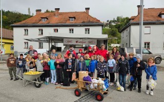 Schulklasse mit Ernte von Äpfeln vor einem Gebäude in Österreich