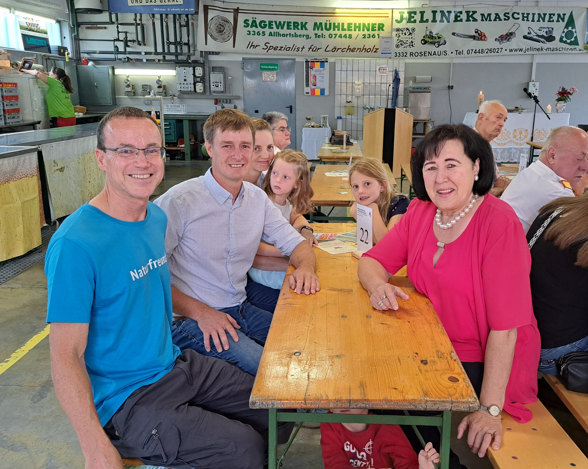 Familie sitzt an Holztisch in Allhartsberg, Niederösterreich, bei Veranstaltung