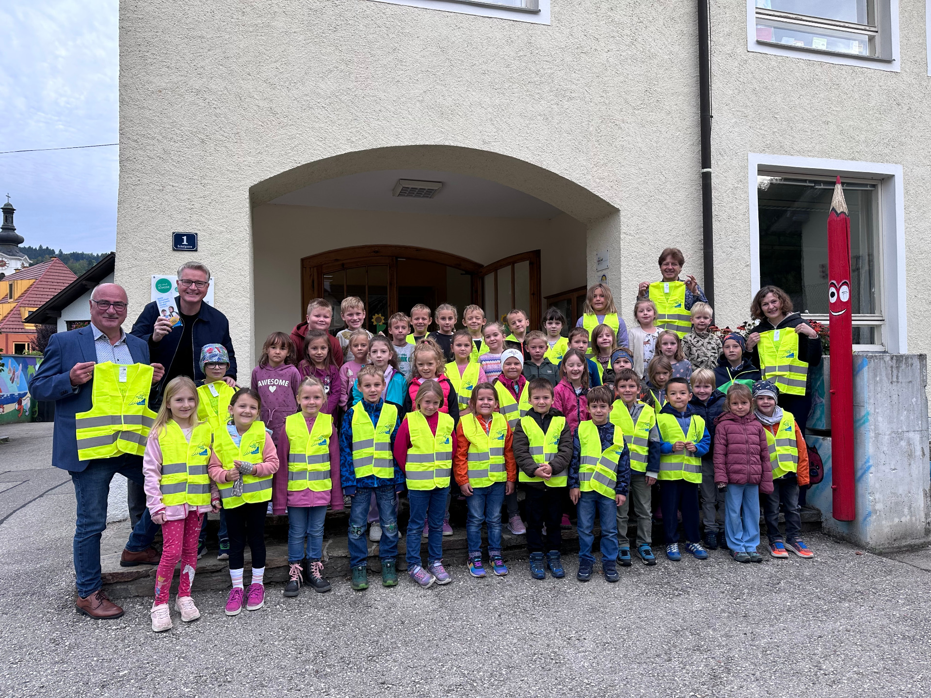 Kindergartenkinder und Erwachsene mit Warnwesten vor einem Gebäude in Obervellach